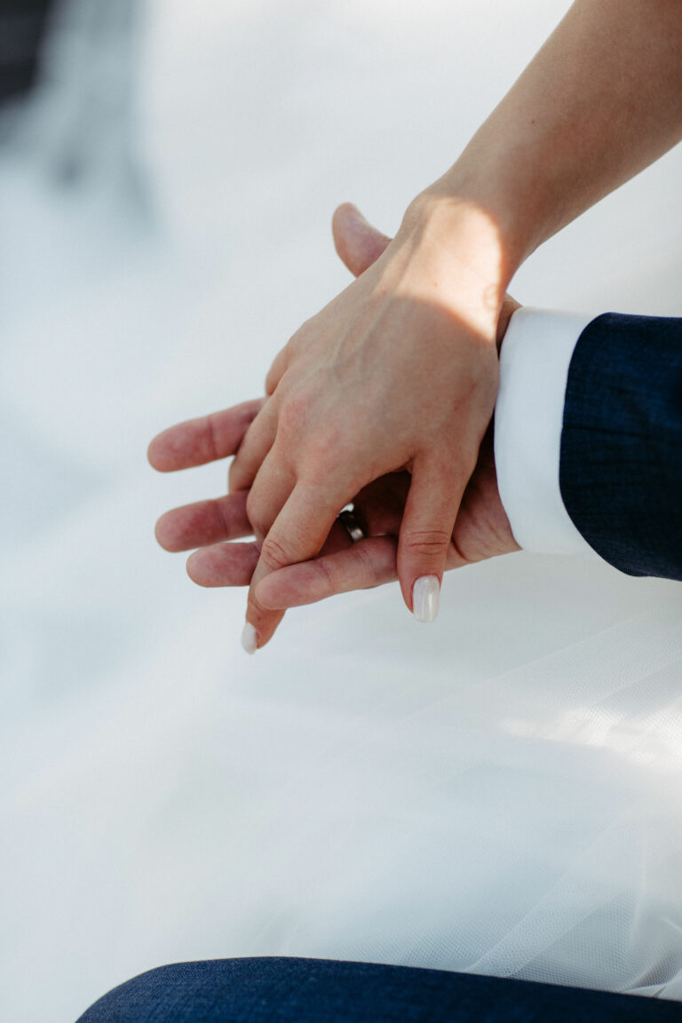 Hochzeitsplanung Braut legt ihre Hand in die des Bräutigams